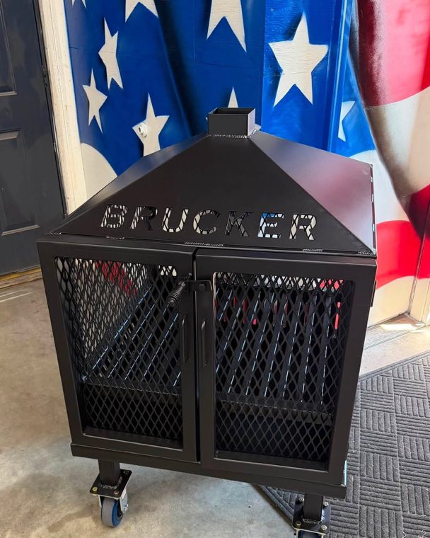 Custom fabricated steel fire pit with doors, a top, and casters, in front of an American flag