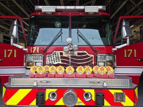 Champaign Firefighters Local 1260 5K awards lined up on the front bumper of a Champaign fire engine