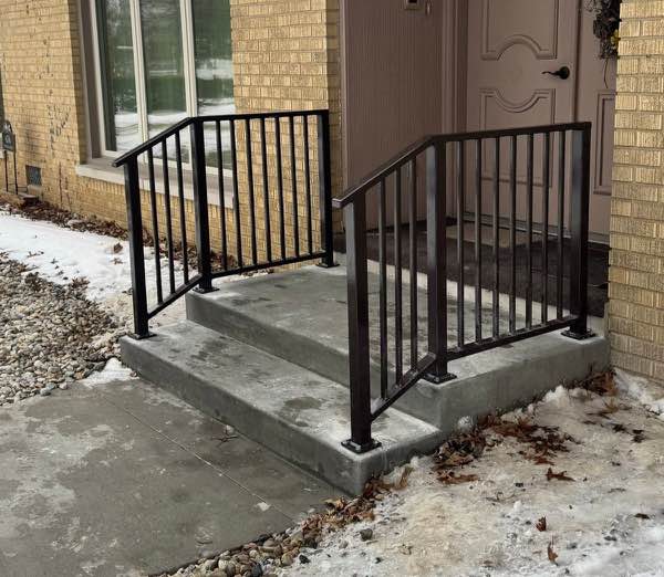 Pair of black powder coated steel railings on a new concrete front porch