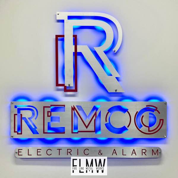 Backlit brushed aluminum business sign with red highlights at the main entrance of the Remco Alarm and Electric building