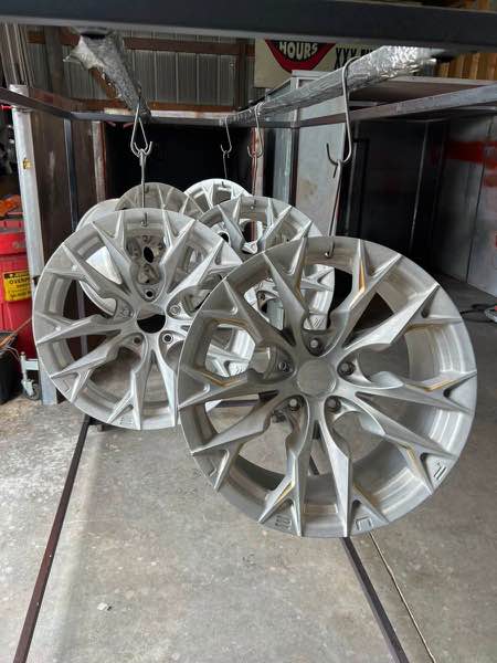 Set of wheels stripped and hanging on the rack before sandblasting